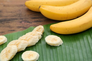 Photo of Delicious ripe bananas and fresh leaf on wooden table