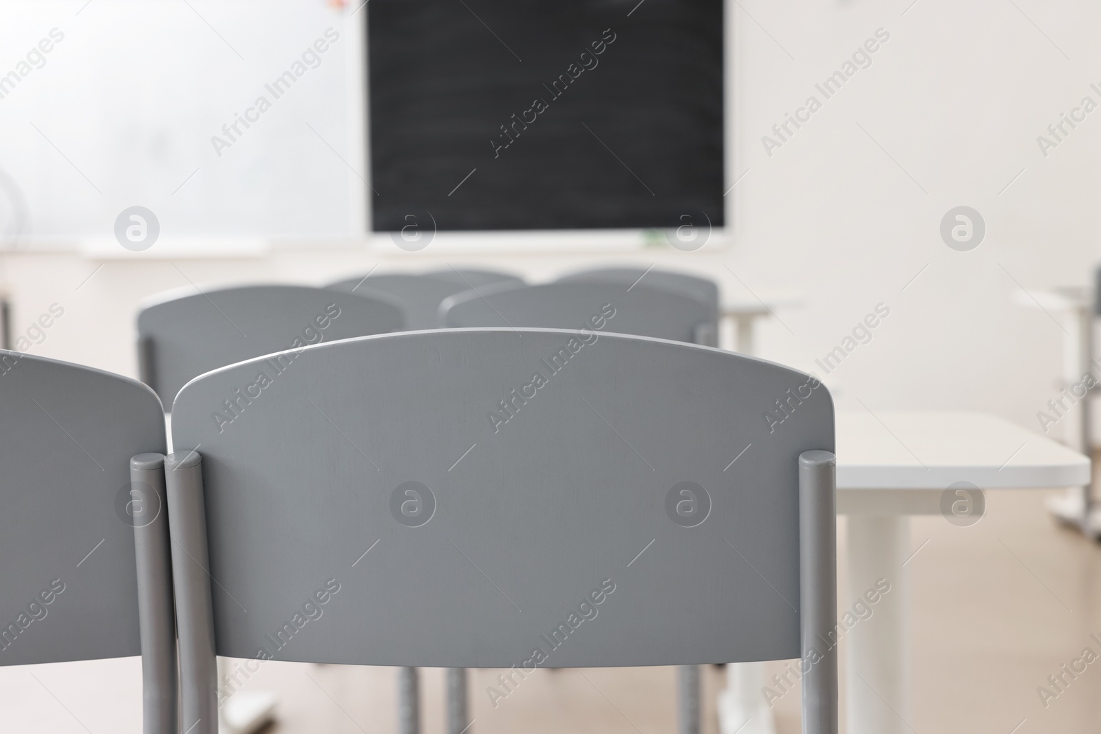 Photo of Empty school classroom with desks, blackboard and chairs