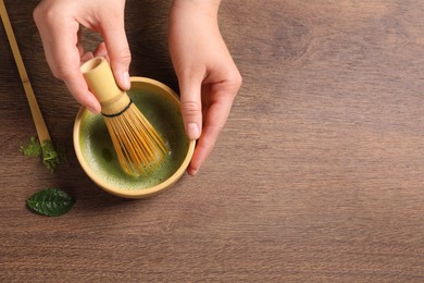 Photo of Woman preparing matcha tea at wooden table, top view. Space for text