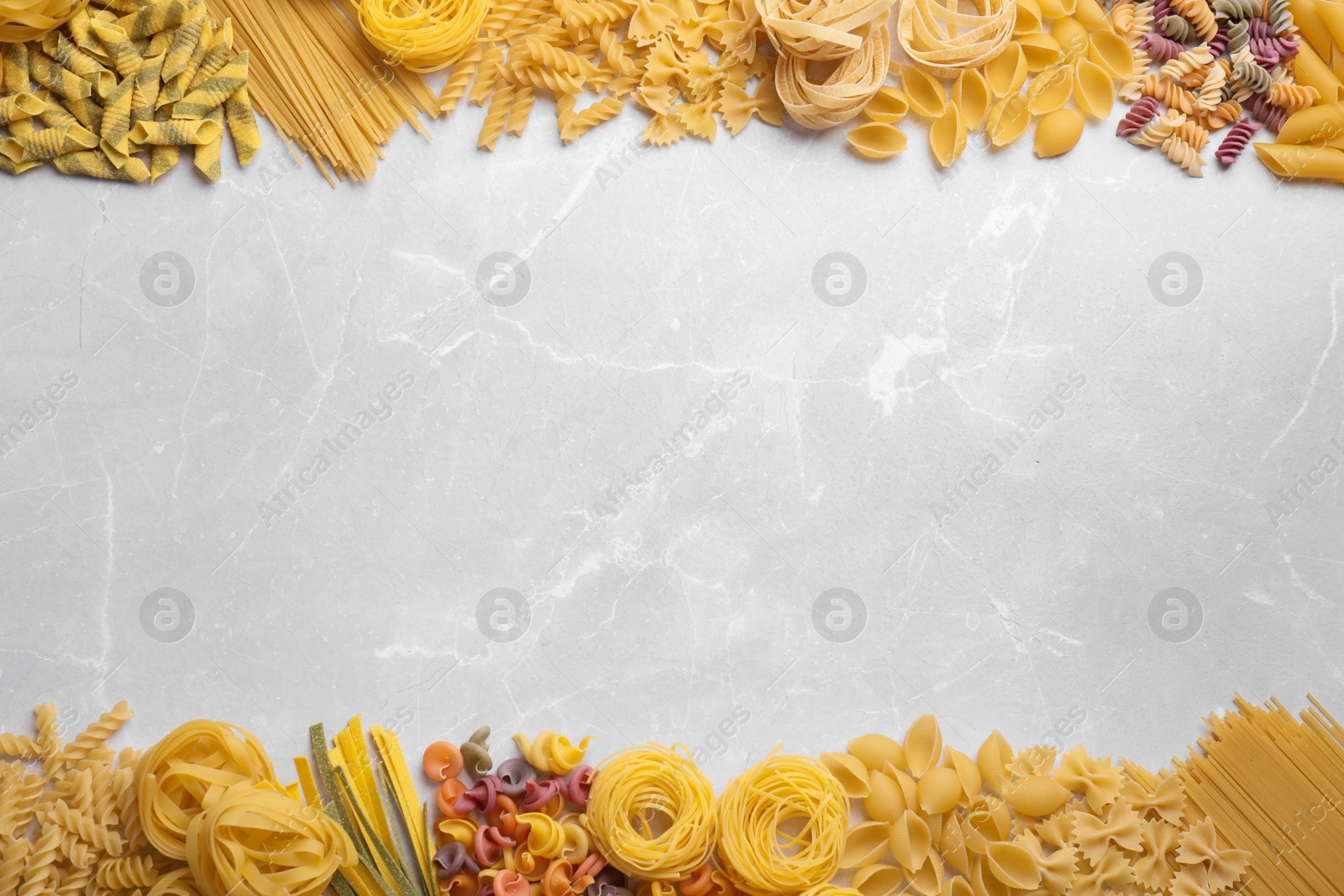 Photo of Different types of pasta on light grey marble table, flat lay. Space for text