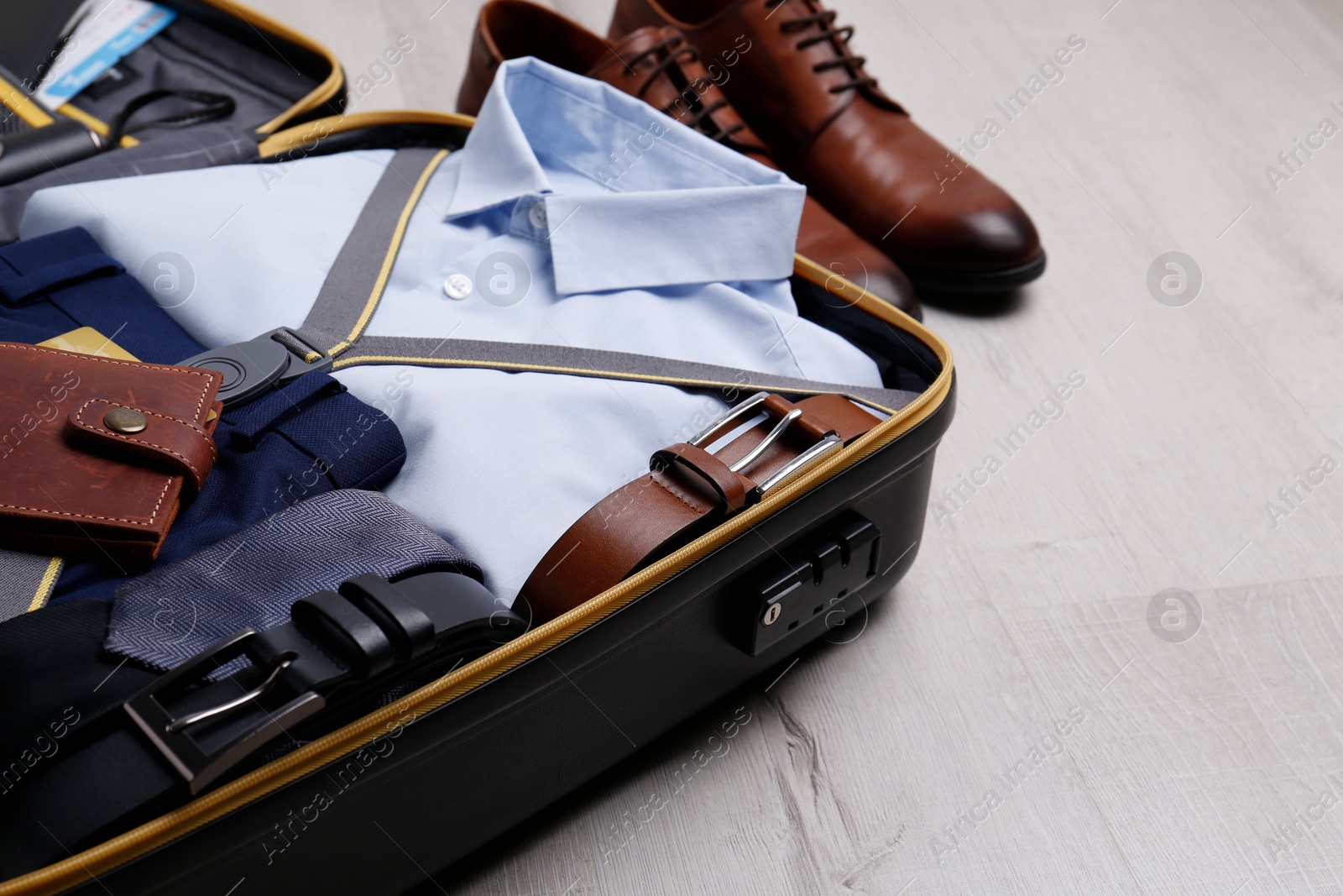 Photo of Packed suitcase with business trip stuff on wooden surface. Space for text