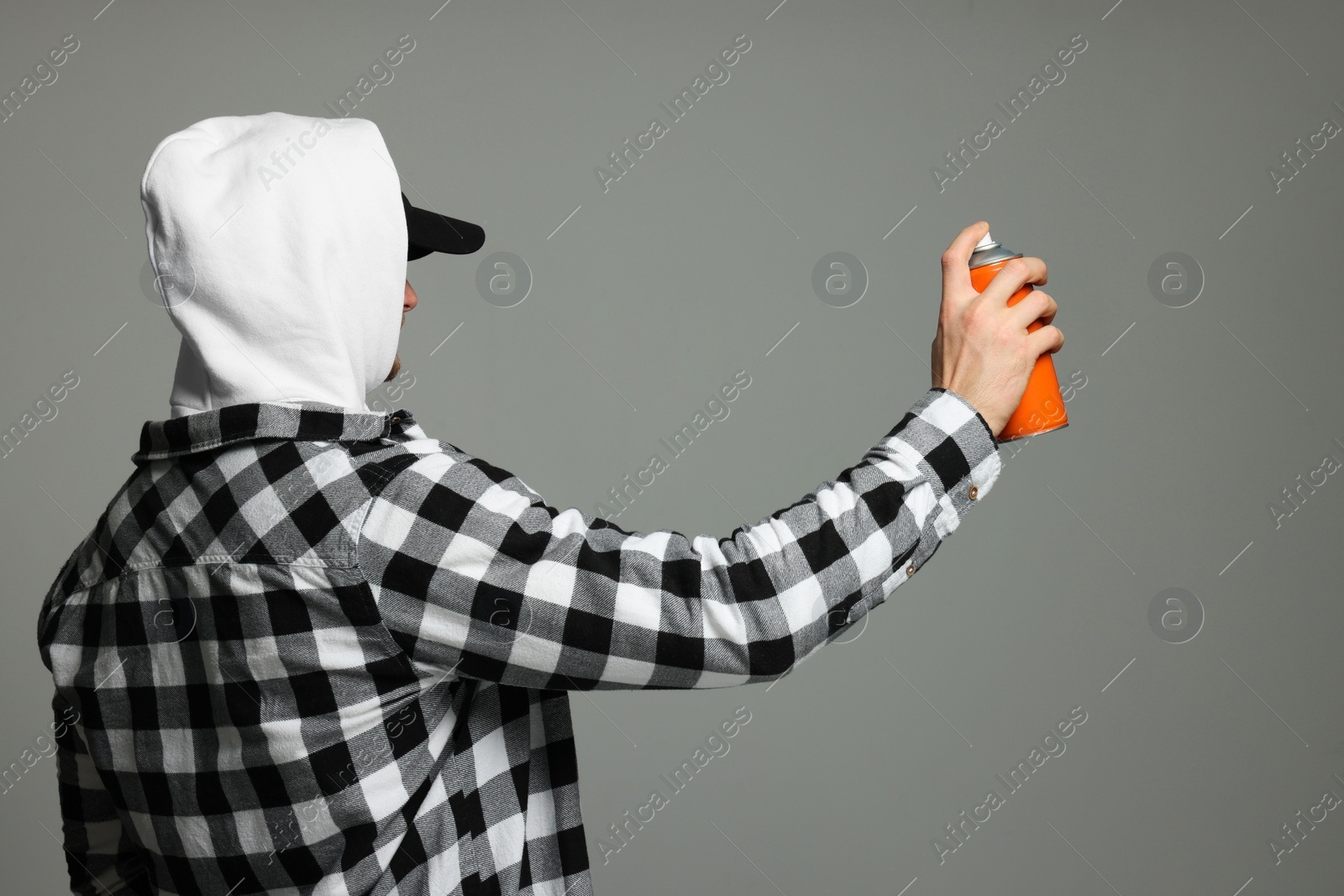 Photo of Man holding orange can of spray paint on grey background