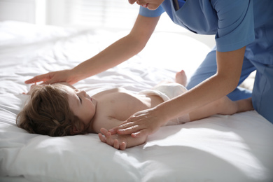 Orthopedist examining cute little baby on bed