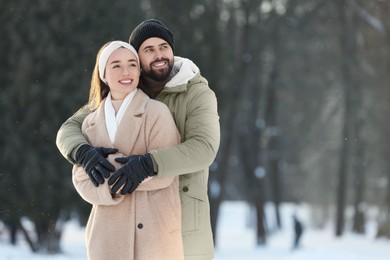 Beautiful young couple enjoying winter day outdoors. Space for text