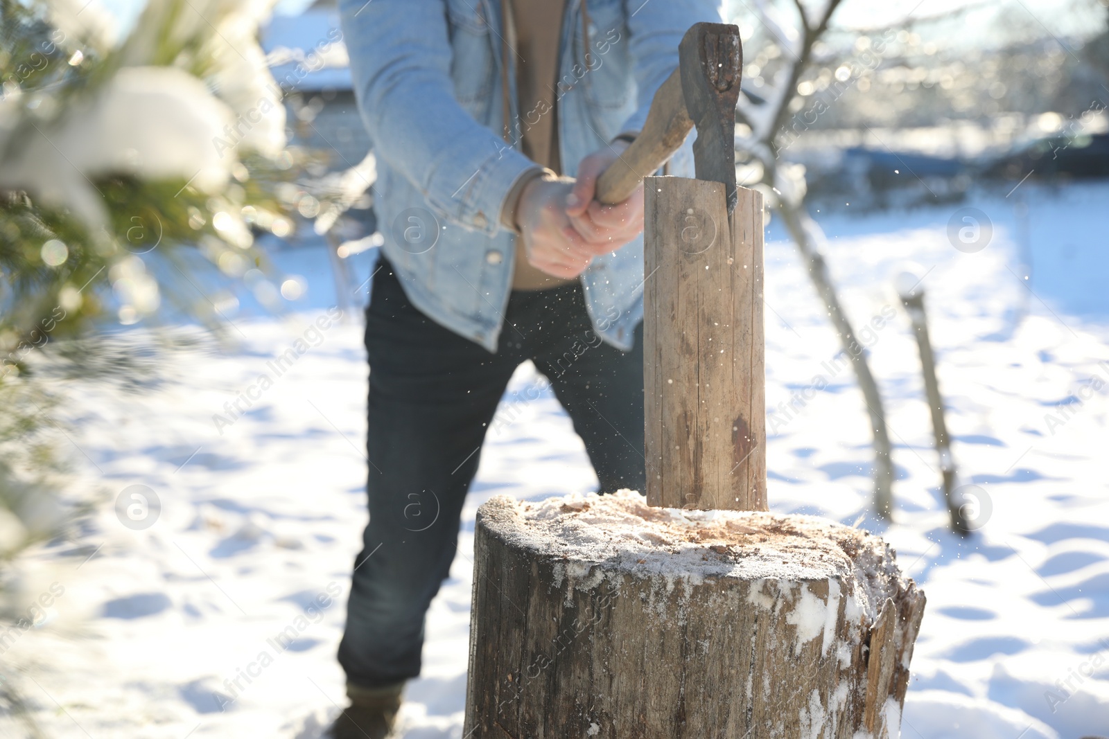 Photo of Man chopping wood with axe outdoors on winter day, closeup