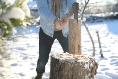 Man chopping wood with axe outdoors on winter day, closeup