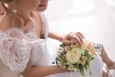 Photo of Young bride with beautiful wedding bouquet in room, closeup