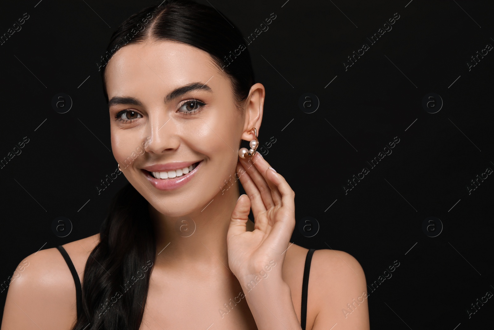 Photo of Young woman with elegant pearl earrings on black background, space for text