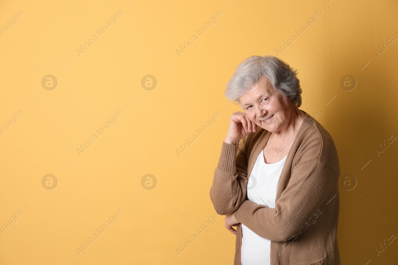 Photo of Portrait of grandmother in stylish clothes on color background, space for text