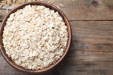 Photo of Bowl with oatmeal on wooden table, flat lay. Space for text