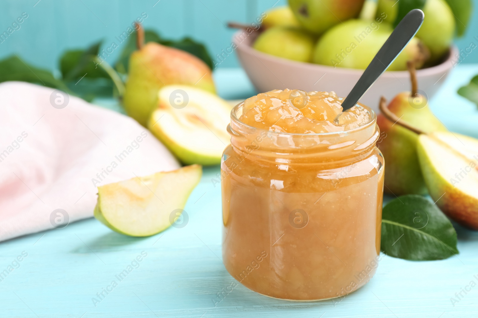 Photo of Tasty homemade pear jam and fresh fruits on light blue wooden table