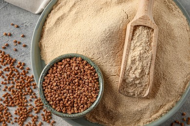 Photo of Flat lay composition with bowl of buckwheat flour and grains on grey table