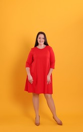 Photo of Beautiful overweight woman in red dress on yellow background