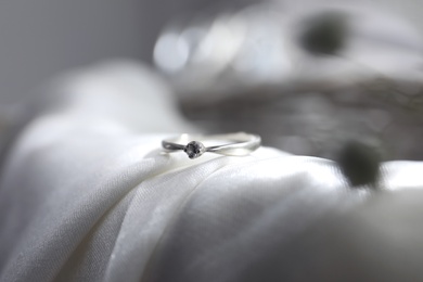 Photo of Beautiful engagement ring on wedding dress, closeup