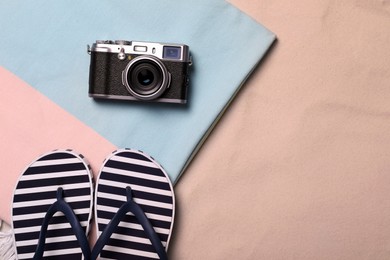 Beach towel, camera and flip flops on sand, flat lay. Space for text