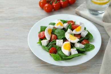 Photo of Delicious salad with boiled eggs, feta cheese and tomatoes on wooden table