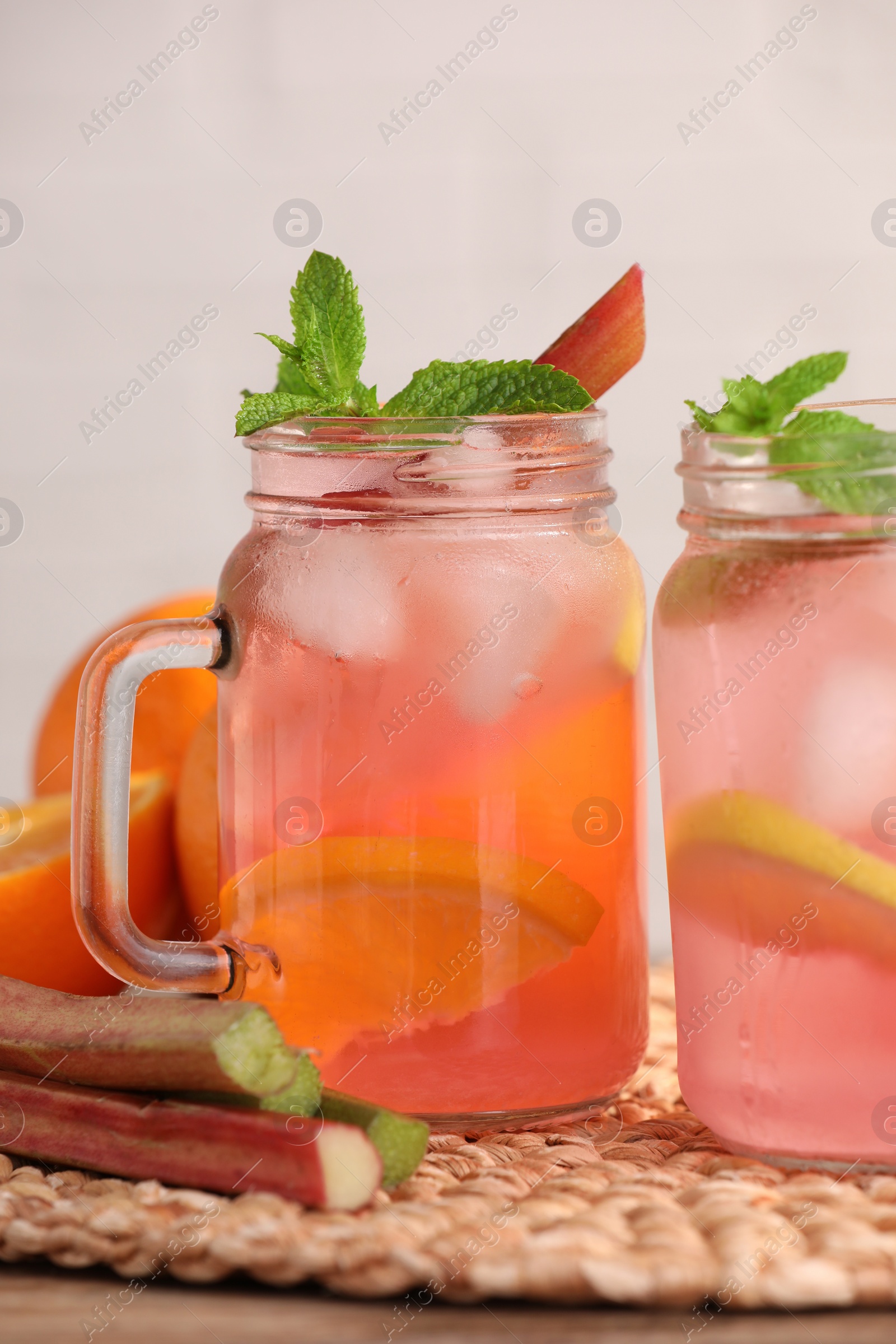 Photo of Mason jars of tasty rhubarb cocktail and lemon on table