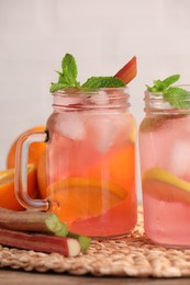 Photo of Mason jars of tasty rhubarb cocktail and lemon on table