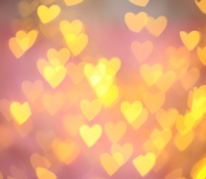 Photo of Blurred view of gold heart shaped lights on pink background