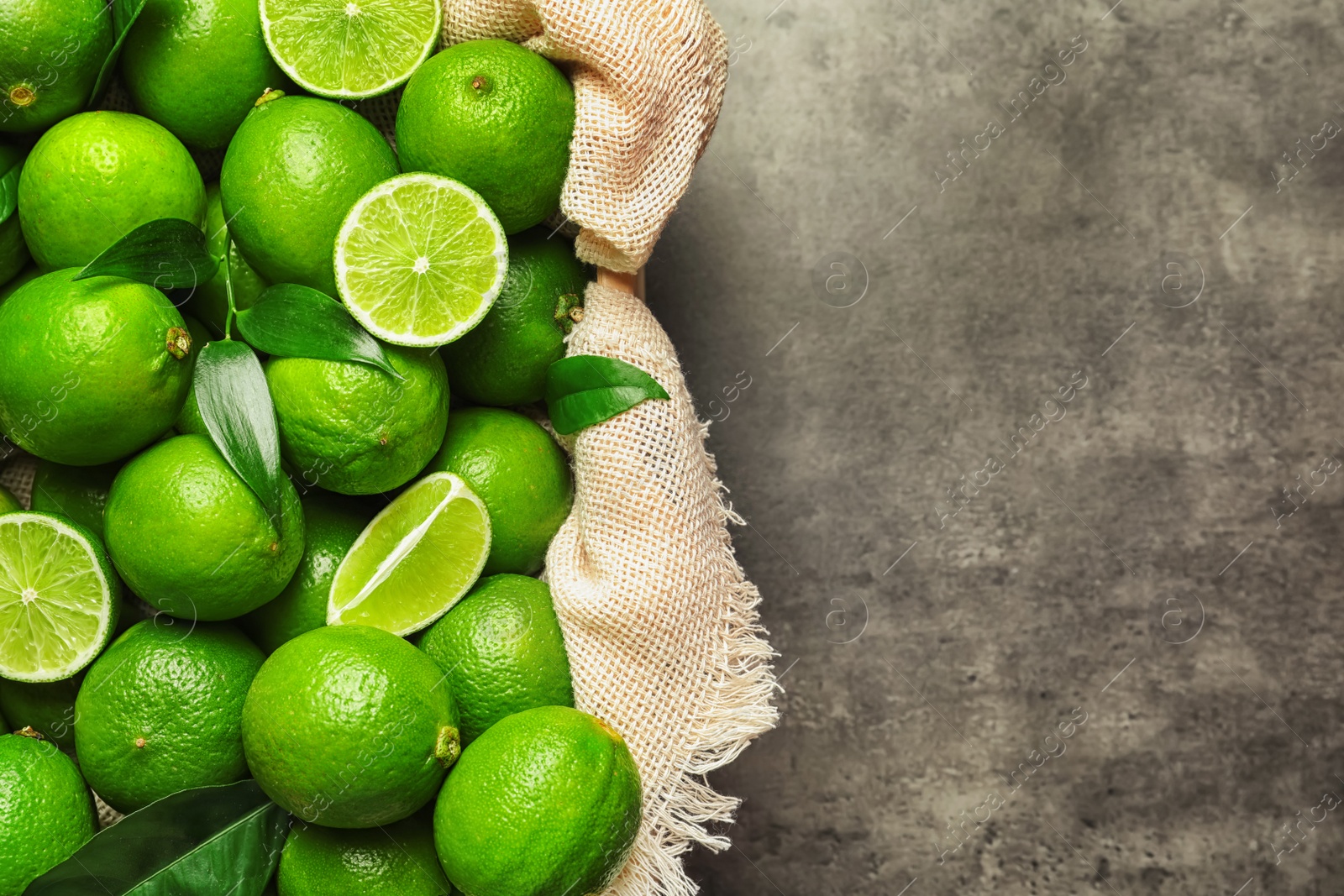 Photo of Crate with fresh ripe limes on gray background, top view