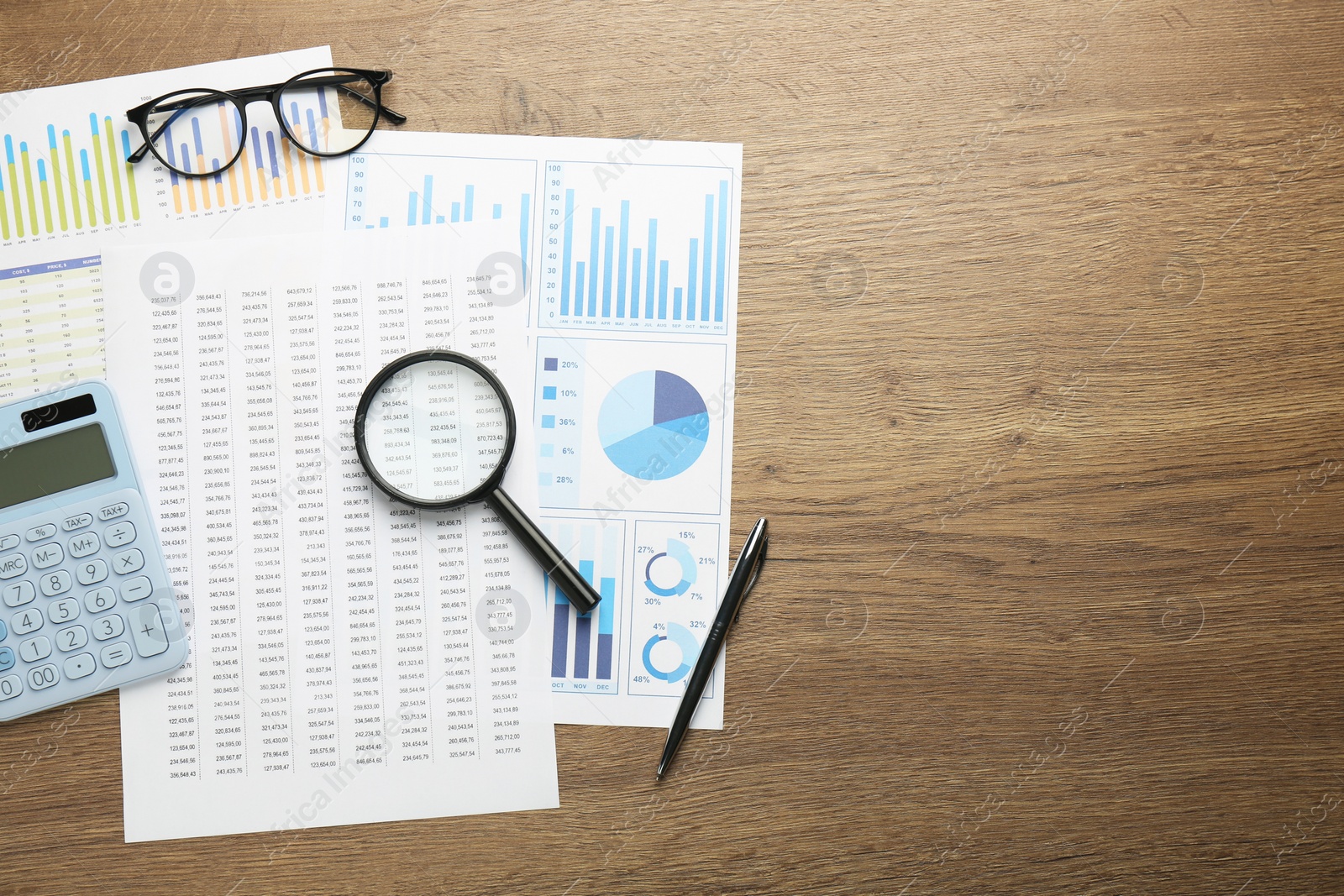 Photo of Accounting documents, magnifying glass, stationery and glasses on wooden table, top view. Space for text