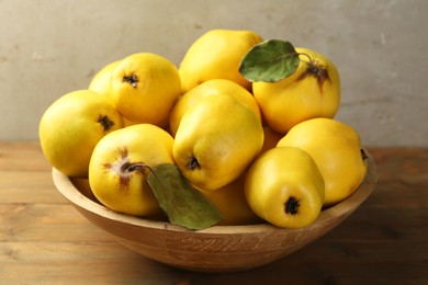 Tasty ripe quince fruits in bowl on wooden table