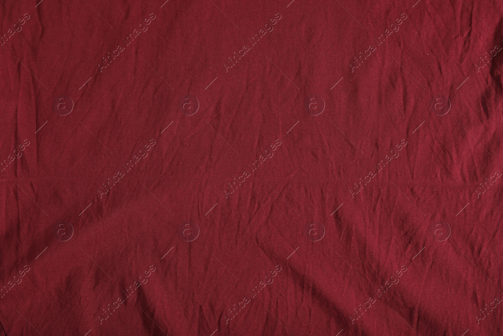 Photo of Crumpled dark red fabric as background, top view