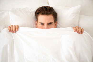 Man under blanket in bed at home, top view. Lazy morning