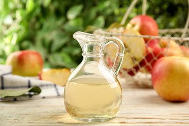 Natural apple vinegar and fresh fruits on white wooden table