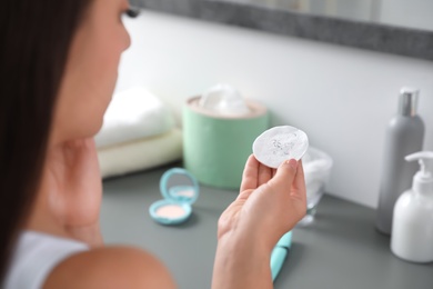 Photo of Young woman holding cotton pad with fallen eyelashes indoors