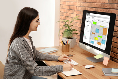 Photo of Young woman using calendar app on computer in office