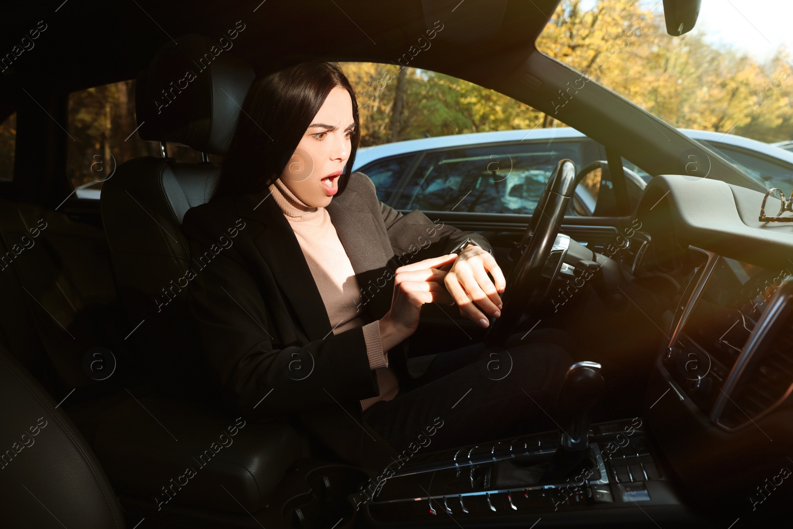 Photo of Emotional woman checking time on watch in car. Being late concept