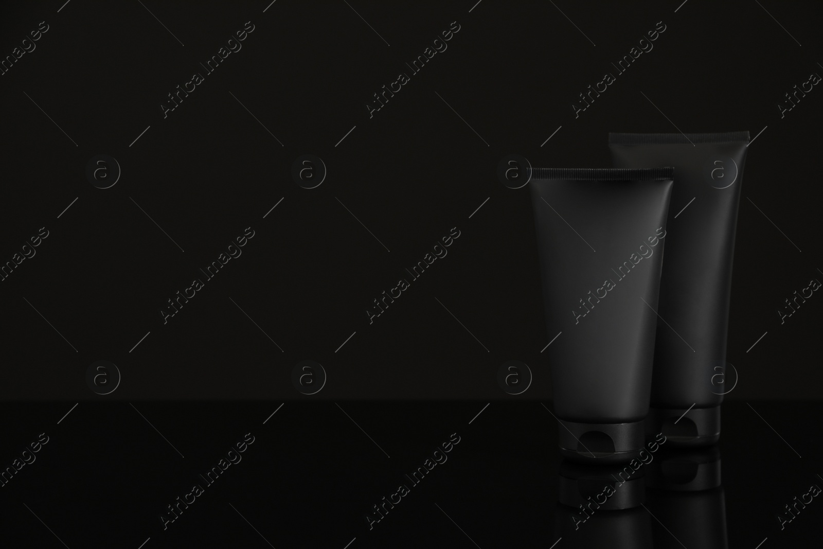 Photo of Tubes of men's facial cream on black background. Space for text