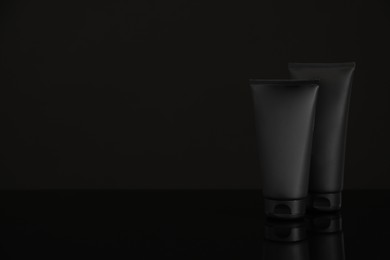 Photo of Tubes of men's facial cream on black background. Space for text