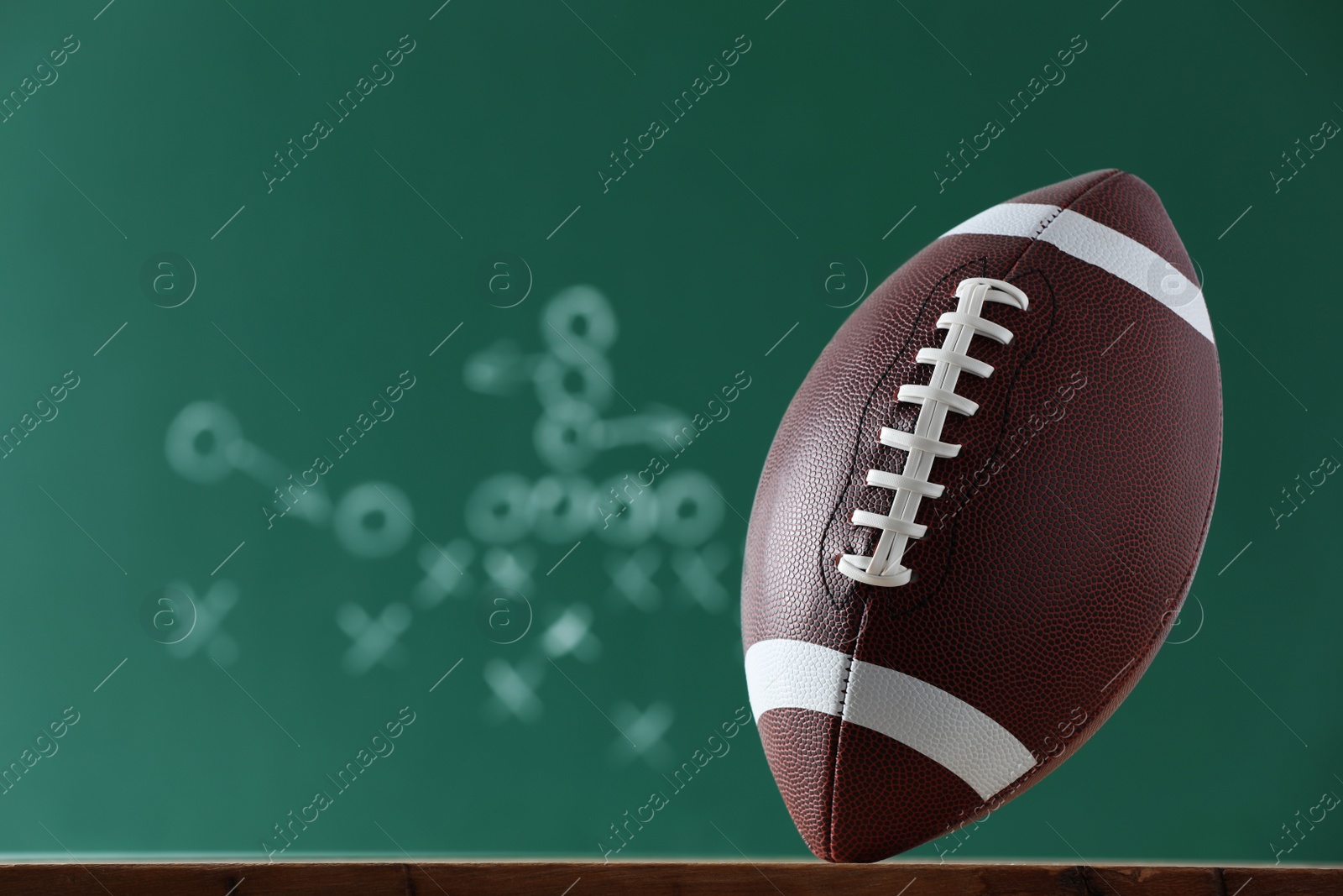 Photo of American football ball against blurred game scheme. Space for text