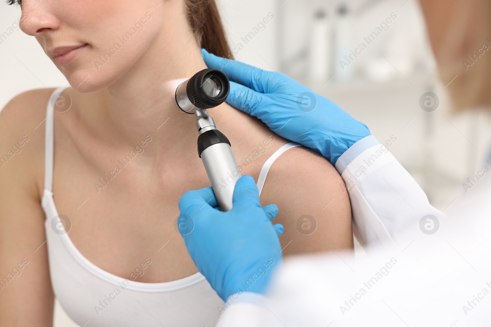 Photo of Dermatologist with dermatoscope examining patient in clinic, closeup