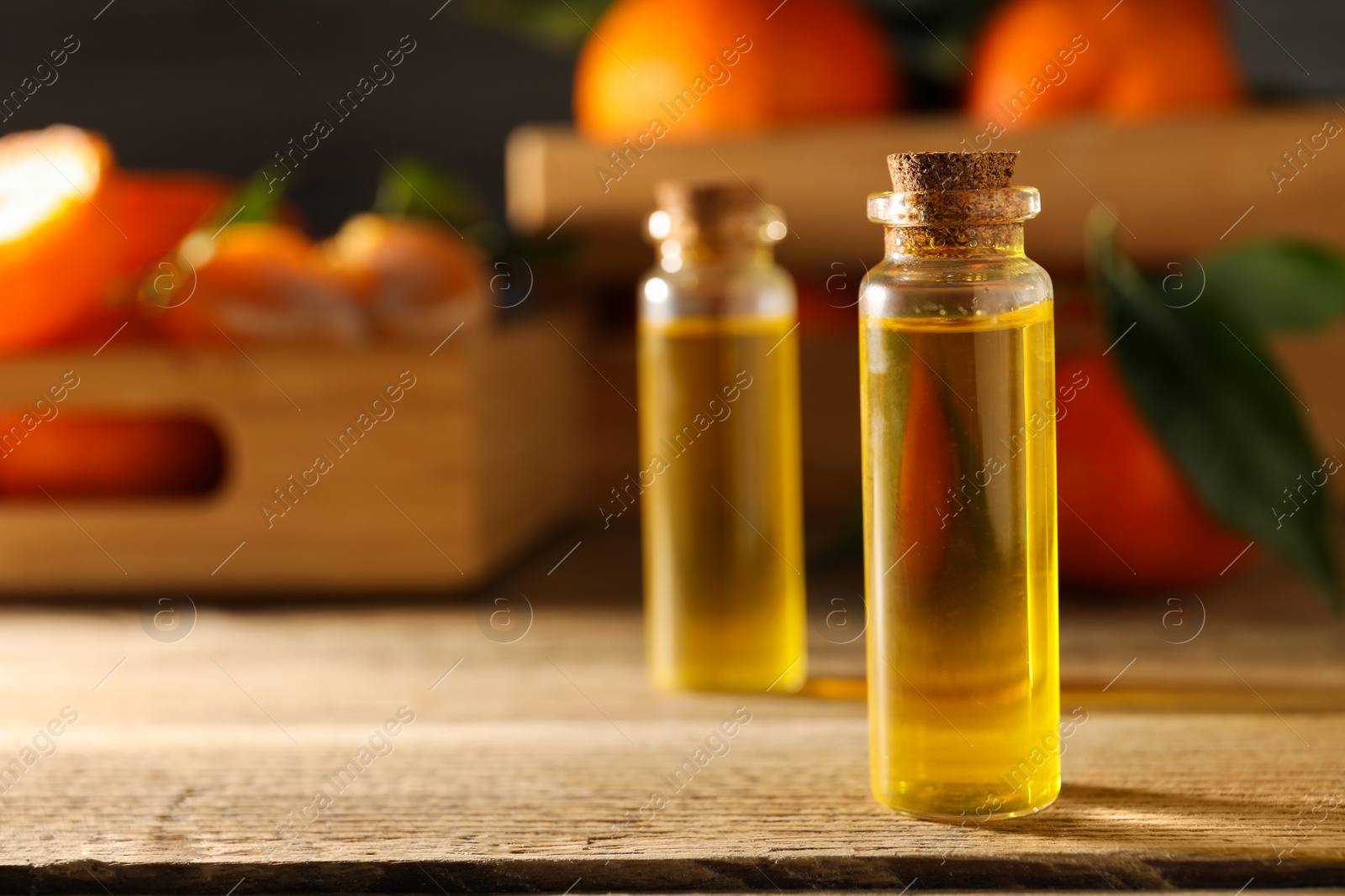 Photo of Bottles of tangerine essential oil on wooden table, closeup