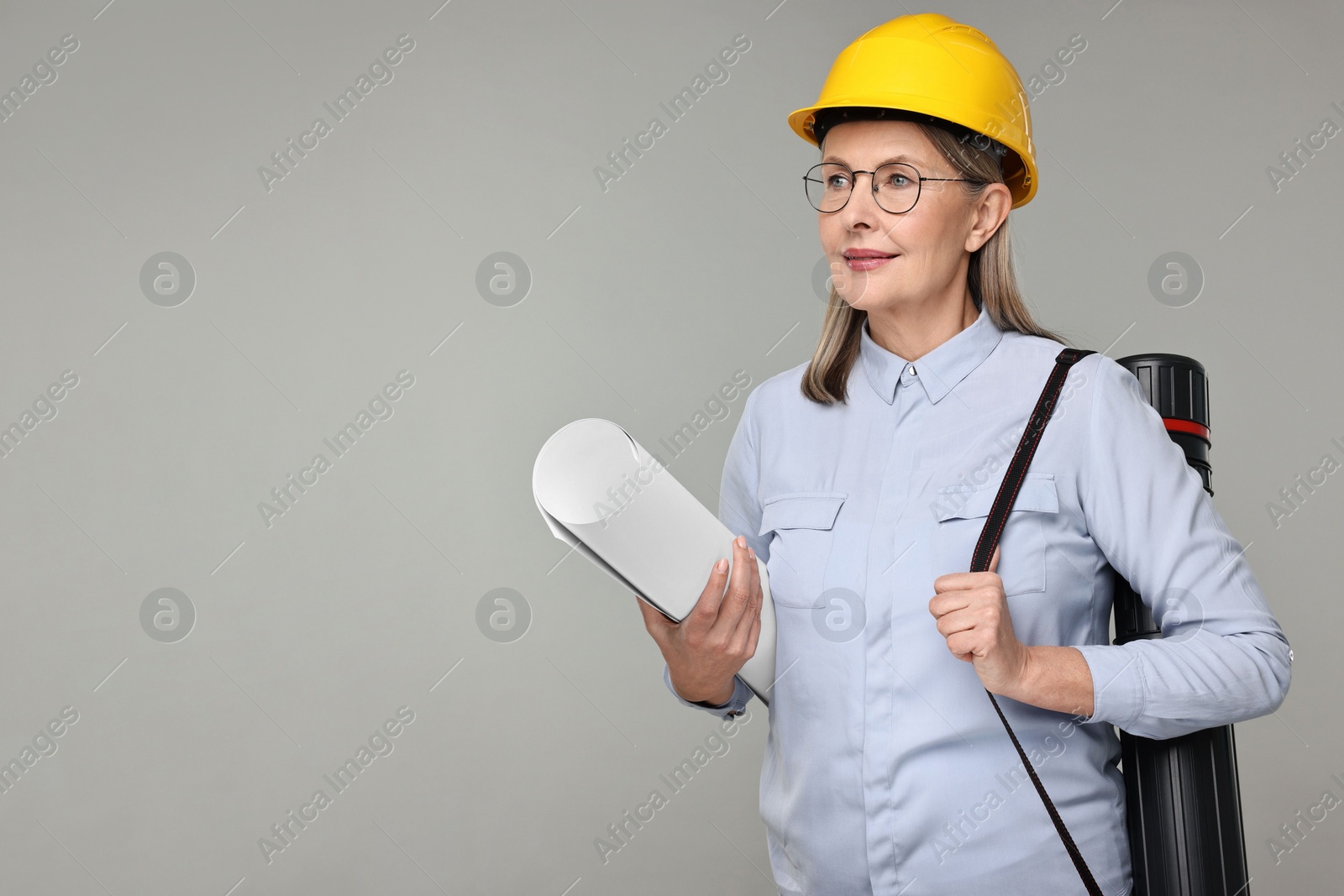 Photo of Architect in hard hat with draft and tube on grey background, space for text