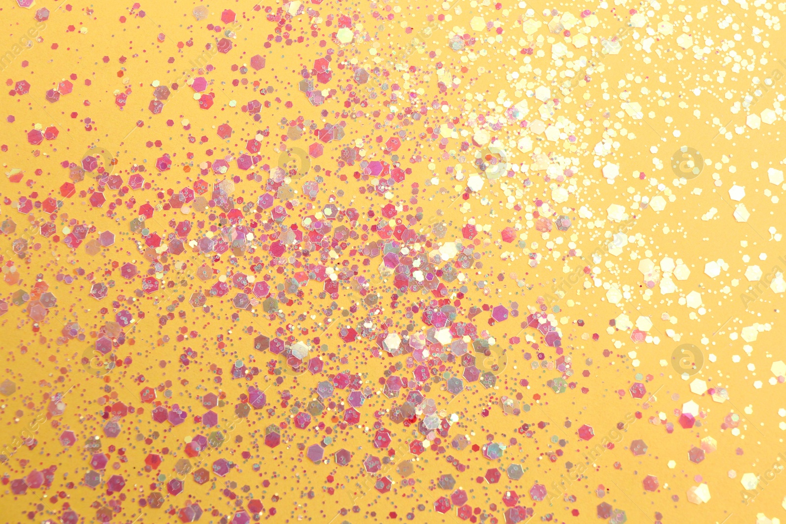 Photo of Shiny bright glitter on yellow background, flat lay