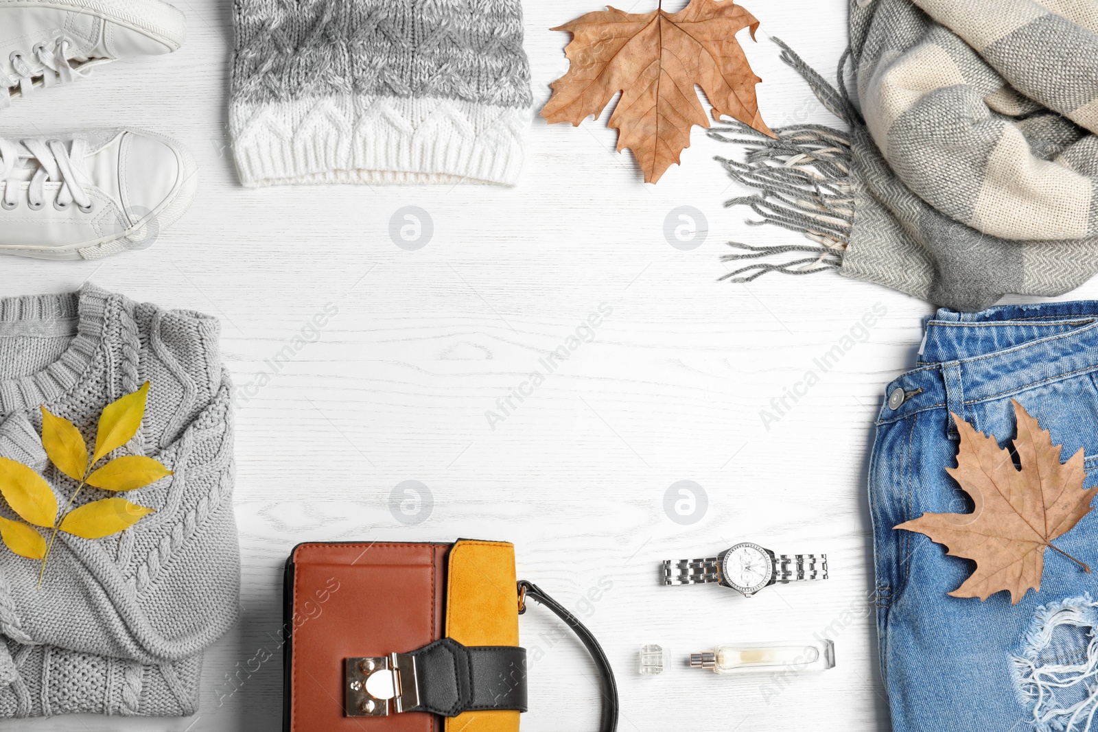 Photo of Stylish outfit and autumn leaves on white wooden background, flat lay with space for text. Trendy warm clothes