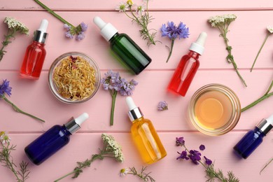 Aromatherapy. Different essential oils and flowers on pink wooden table, flat lay