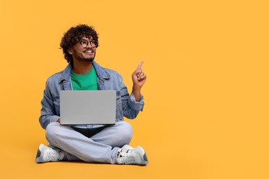 Photo of Smiling man with laptop on yellow background, space for text