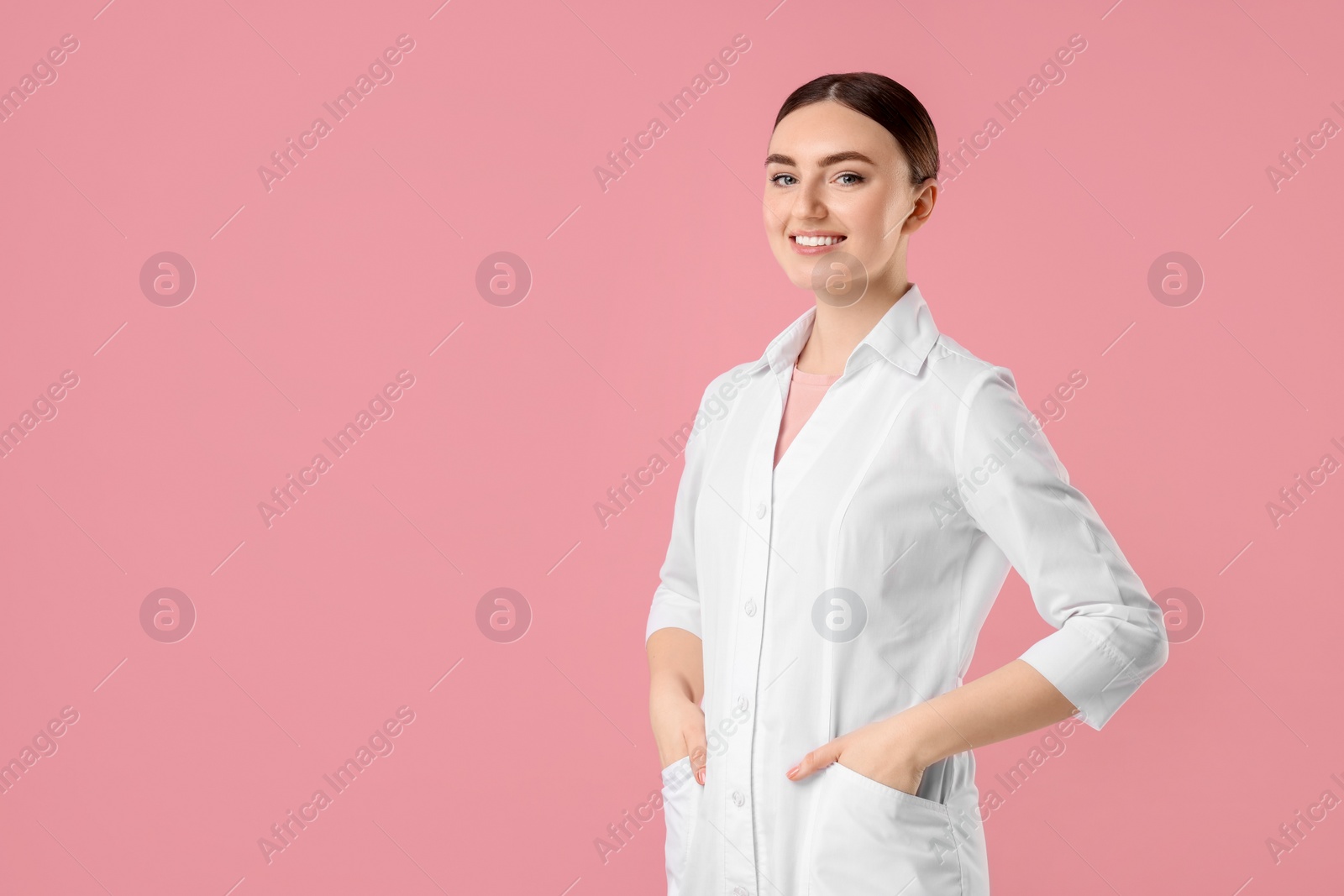 Photo of Cosmetologist in medical uniform on pink background, space for text