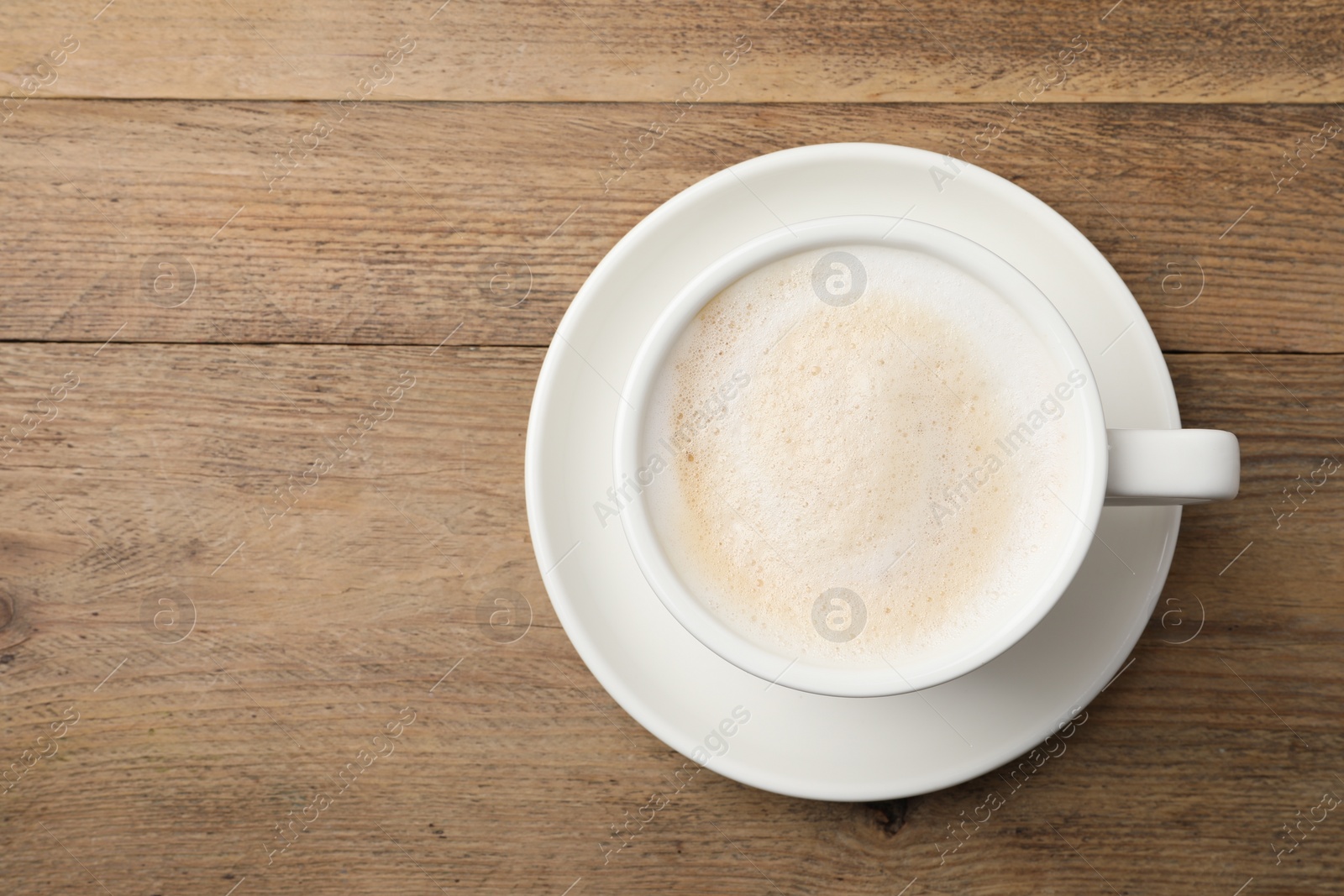 Photo of Cup of aromatic coffee on wooden table, top view. Space for text