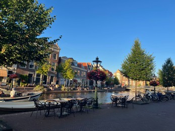 Photo of Leiden, Netherlands - August 1, 2022: Picturesque view of city street with cafe and beautiful buildings along canal