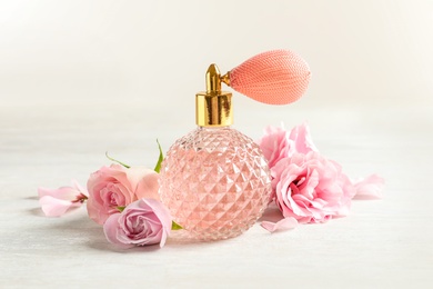Photo of Vintage bottle of perfume and flowers on light background