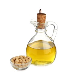 Photo of Glass jug of oil and soybeans on white background