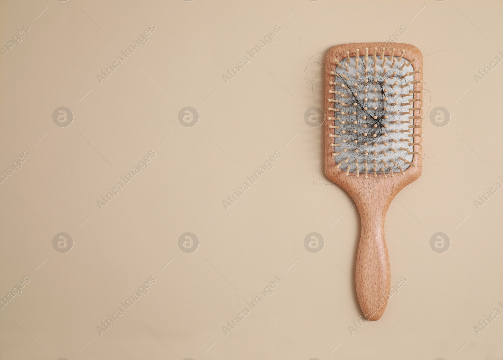 Photo of Wooden brush with lost hair on beige background, top view. Space for text