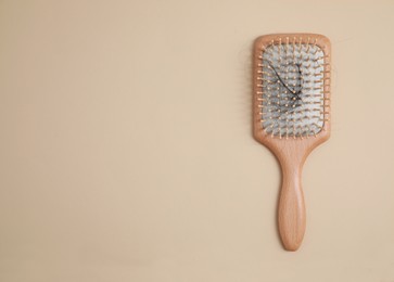 Photo of Wooden brush with lost hair on beige background, top view. Space for text