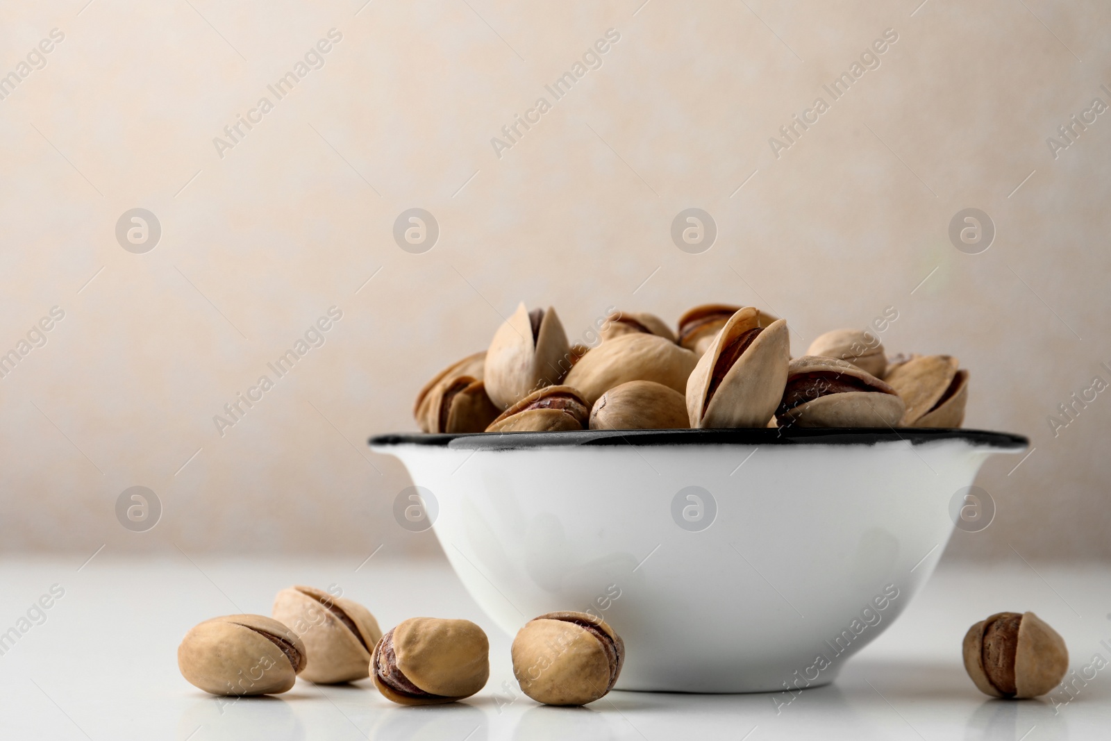 Photo of Bowl and pistachio nuts on white table